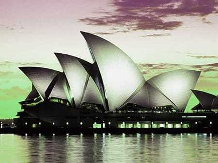 Sydney Opera House with its iconic sail-like structures reflected in the water at dusk. - Olive Oil Times