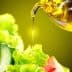 Olive oil being poured from a glass container onto a fresh green salad with lettuce and vegetables. - Olive Oil Times