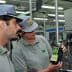 Two individuals examining a bottle of olive oil in a production facility. - Olive Oil Times