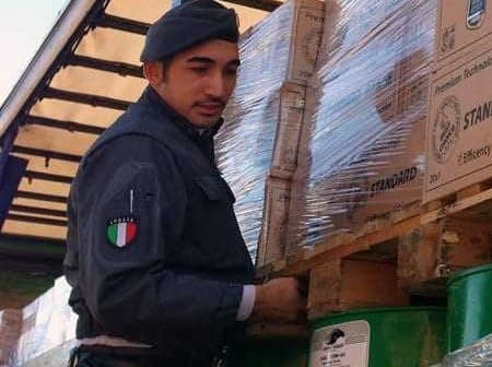 Italian police officer in uniform managing cargo on a truck with boxes and pallets. - Olive Oil Times
