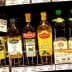 Different brands of olive oil bottles displayed on a supermarket shelf. - Olive Oil Times