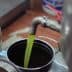 Green olive oil being poured from a metal tap into a container. - Olive Oil Times