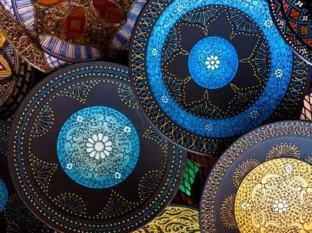Collection of decorative hand-painted ceramic plates featuring intricate designs in various colors. - Olive Oil Times