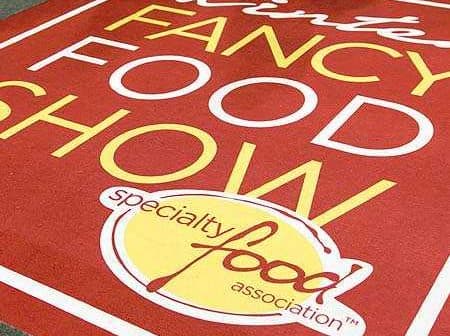 Red carpet with the text 'Winter Fancy Food Show' and 'Specialty Food Association' in yellow and white. - Olive Oil Times