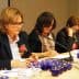 Three women seated at a conference table with blue tasting cups in front of them, engaged in discussion. - Olive Oil Times
