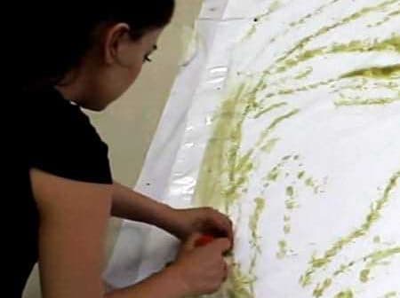 Individual applying olive oil to a large sheet of white paper to create artwork. - Olive Oil Times