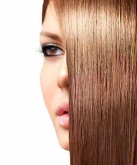 Close-up view of a woman's face partially obscured by smooth, straight brown hair. - Olive Oil Times