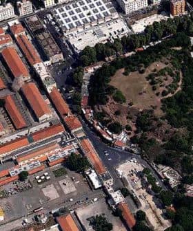 Aerial view showing a mix of buildings and a green park area in an urban setting. - Olive Oil Times