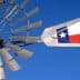 Close-up of a windmill with a Texas state flag attached to its arm against a blue sky. - Olive Oil Times
