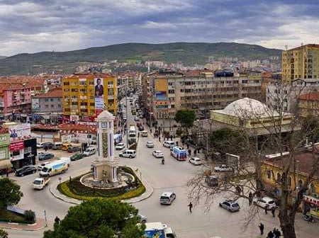 Aerial view of a Turkish town featuring a clock tower and surrounding buildings. - Olive Oil Times