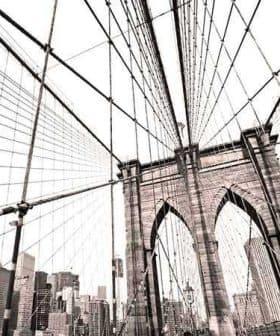 View of the Brooklyn Bridge's structure with cables and city skyline in the background. - Olive Oil Times