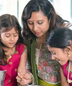 A woman and two girls engaged in cooking together, wearing traditional attire in a kitchen setting. - Olive Oil Times