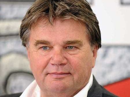 A man with short brown hair and blue eyes wearing a white shirt and dark suit jacket. - Olive Oil Times