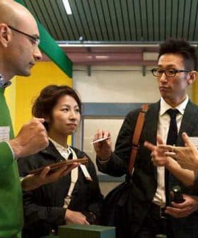 A group of four professionals discussing with tablets and pens in a modern setting. - Olive Oil Times