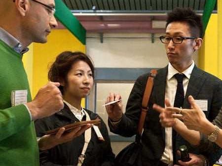 A group of four professionals discussing with tablets and pens in a modern setting. - Olive Oil Times