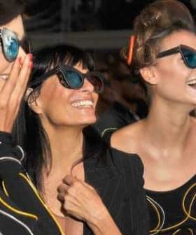 Three women smiling and wearing sunglasses at an event, showcasing various styles of eyewear. - Olive Oil Times