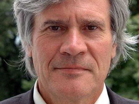 Close-up portrait of a man with gray hair wearing a suit and a neutral expression. - Olive Oil Times