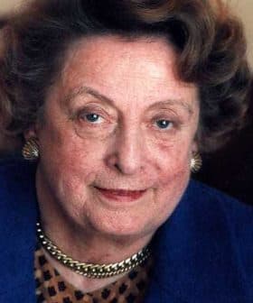 Close-up portrait of a woman with curly hair and blue eyes wearing a blue jacket. - Olive Oil Times