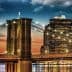 Brooklyn Bridge with illuminated towers and city skyline during sunset. - Olive Oil Times