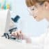 Laboratory technician wearing safety glasses examining a sample under a microscope. - Olive Oil Times