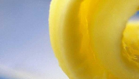 Close-up view of a swirl of olive oil gel against a blue background. - Olive Oil Times