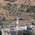 A tall minaret located in a rural area with olive trees in the background. - Olive Oil Times