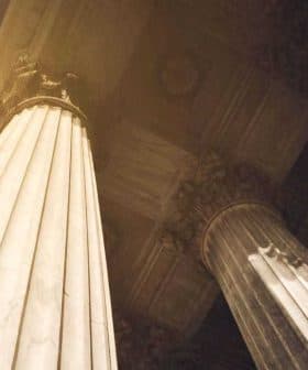 Two large architectural columns with intricate details and a view from below, showcasing their height and design. - Olive Oil Times