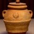 Ceramic pot with a lid, featuring engraved text and decorative patterns on the surface. - Olive Oil Times