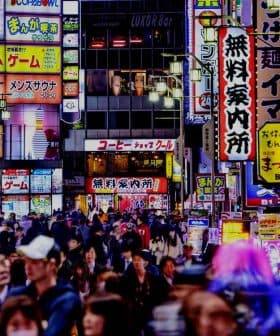 Busy street in Tokyo filled with people and illuminated neon signs in various colors and languages. - Olive Oil Times