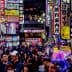 Busy street in Tokyo filled with people and illuminated neon signs in various colors and languages. - Olive Oil Times