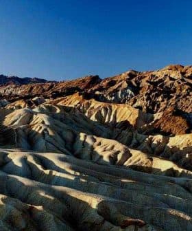 Textured hills and ridges in a desert landscape under a clear blue sky. - Olive Oil Times