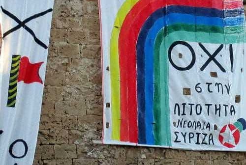 Two large banners with political messages and colorful designs displayed on a stone wall. - Olive Oil Times