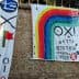 Two large banners with political messages and colorful designs displayed on a stone wall. - Olive Oil Times