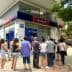 Customers waiting in line outside a Eurobank branch in a city setting. - Olive Oil Times