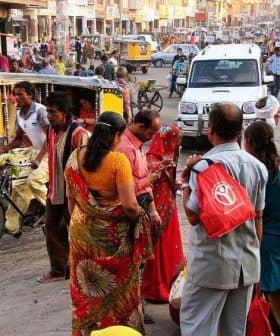 People interacting on a busy street in India with various vehicles and pedestrians present. - Olive Oil Times