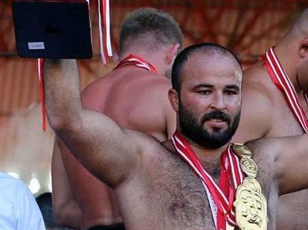Athlete celebrating victory by holding a trophy and wearing multiple medals at a competition. - Olive Oil Times