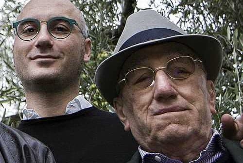 Two men standing together outdoors, one wearing glasses and a hat, the other with glasses and a dark sweater. - Olive Oil Times