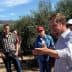 A group of people gathered in an olive grove, with one person speaking to the others. - Olive Oil Times