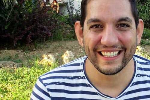 Man with short dark hair wearing a striped shirt, smiling at the camera outdoors. - Olive Oil Times