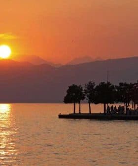 Sunset view over Lake Garda with silhouettes of trees and mountains in the background. - Olive Oil Times