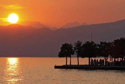 Sunset view over Lake Garda with silhouettes of trees and mountains in the background. - Olive Oil Times