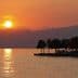 Sunset view over Lake Garda with silhouettes of trees and mountains in the background. - Olive Oil Times
