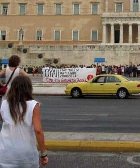 A group of people holding a protest banner in front of a government building. - Olive Oil Times