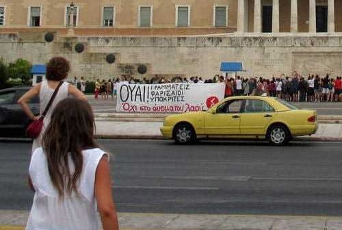A group of people holding a protest banner in front of a government building. - Olive Oil Times