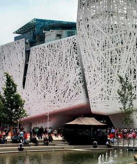 Contemporary building featuring a unique, intricate exterior design with people gathered around a water feature. - Olive Oil Times