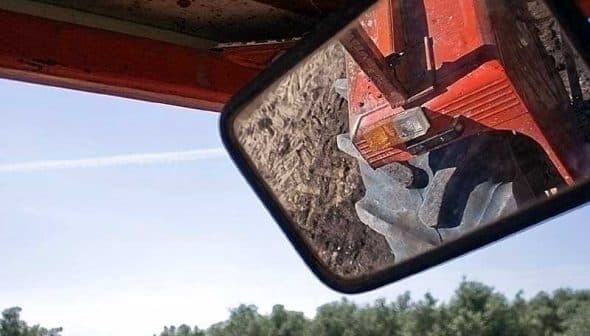Reflection of a tractor's rear light in the side mirror while parked in an olive grove. - Olive Oil Times
