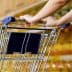 Close-up of a person's hand holding the handle of a shopping cart in a store. - Olive Oil Times