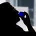 Silhouette of a person holding a blue glass to their lips while drinking. - Olive Oil Times