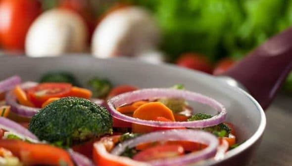 A pan filled with a colorful mix of sliced vegetables including broccoli, carrots, and red onions. - Olive Oil Times