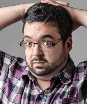 Man with glasses and a plaid shirt holding his head with both hands, looking surprised. - Olive Oil Times